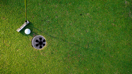 white golf ball in hole on green grass good for background with sunlight.