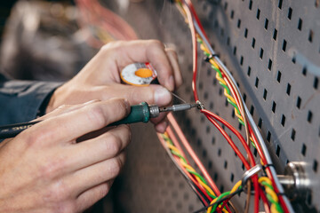 Close up hands of engineer soldering wires