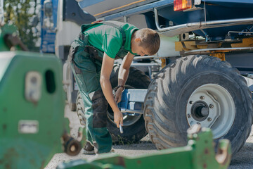Young mechanic repair tractor outdoor	
