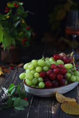 A bowl with red and green grape in rustic style