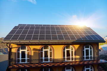 Solar panels on small wood board domestic house roof, sustainable energy concept.