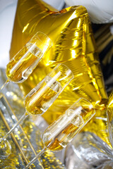 Close up of shiny glasses of champagne over golden and silver balloons background