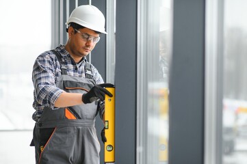 The worker installs a window frame in the room