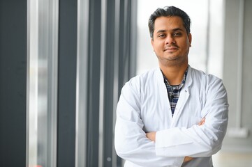Portrait of male indian doctor on clinic corridor as background.