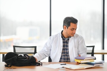 Portrait of a young Indian male medical student in a white coat waving