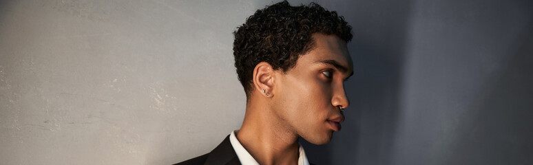 attractive young african american man with accessories in black suit posing and looking away, banner