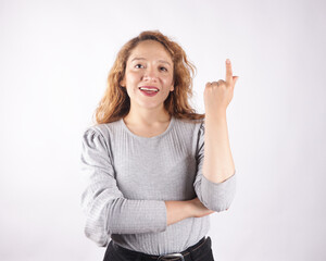 Photograph of white latina woman on light background pointing upwards.