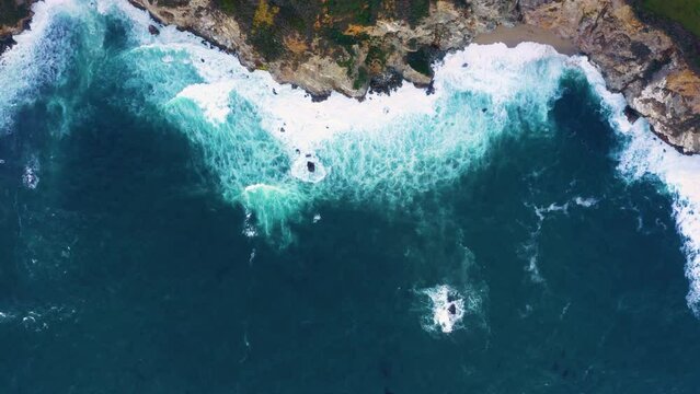 Aerial view looking straight down onto crashing waves. Blue ocean, wave and impact power.