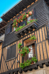 Fotografía vertical de arquitectura tradicional con balcones ornamentados con multitud de macetas...