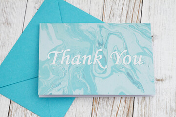 Fototapeta na wymiar Thank you greeting card with blue envelope and on wood