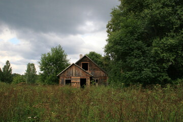 abandoned old wooden house near forest in Lithuania and stormy sky