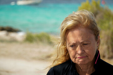 Sad mature woman in a windy beach