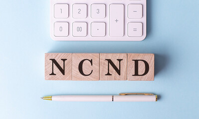 NCND on wooden cubes with pen and calculator, financial concept