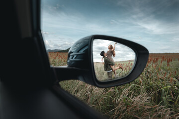 The side mirror of a car with the reflection of a couple holding each other