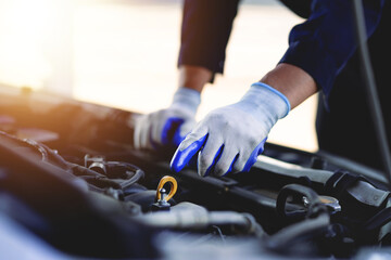 Auto mechanic checking oil in car engine Technician inspects and maintains car engines.
