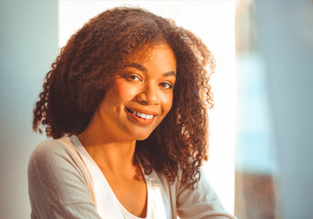 Fototapeta na wymiar Pleased relaxed African American ethnicity girl in homewear sitting on windowsill