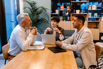 Group of mixed age colleagues discussing business issues during meeting in conference room