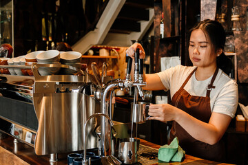 Young woman barista making coffee in coffee shop counter