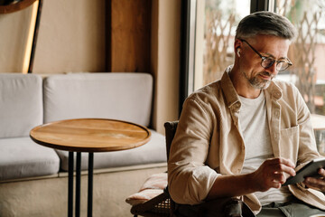 Portrait of smiling man using tablet while sitting in cafe