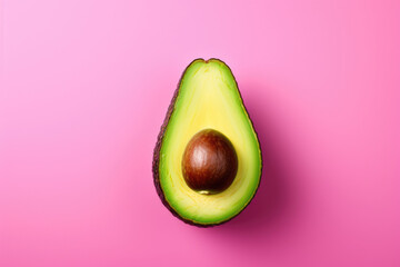 Ripe cut avocado with a pit on a pink background