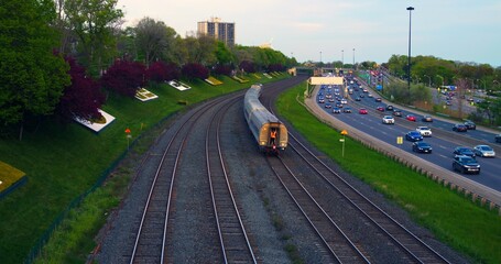 Railroad with train alongside highway filled with flowing traffic Train as symbol of journey mirroring road activity. Train and traffic intertwined paths of movement life's vibrant rhythm.