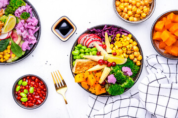 Vegan buddha bowl with sweet potato, quinoa, chickpeas, soybeans edamame, tofu, corn, cabbage, radish, broccoli and seeds, white table background, top view. Healthy vegetarian comfort food