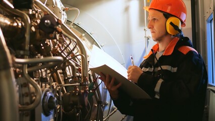 Industrial worker inspects turbine pre-engine start in industrial setting. Showcases industrial...