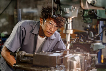 Engineer worker in production plant drilling at machine. Professional worker near drilling machine on factory. man inspecting and repairing machine for operation in workshop.