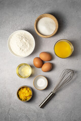 Baking ingredients, oil, sugar, flour, eggs and milk with whisk. Top view.