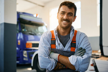 Happy mechanic at truck repair shop looking at camera.