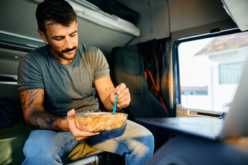 Professional truck driver having lunch in vehicle cabin.