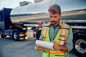 Freight transportation manager going through check list on a parking lot.
