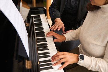 Close-up view of women hands playing piano indoor