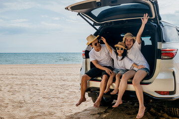 Family Day. Father, Mother and daughter enjoying road trip sitting on family back car raise hand...