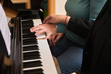 Close-up two women musicians pianists playing the piano in four hands, studying a new musical composition. Music lesson