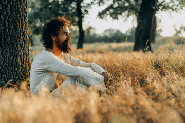 A photograph featuring a person portraying Jesus Christ, meditating and praying at sunset in a...