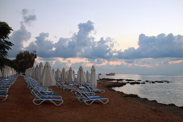 Loungers, umbrella. Resort hotel. Rows of folded beach umbrellas and empty sunbeds on the beach....