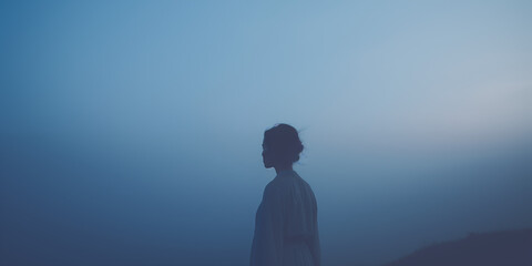 Silhouette of a woman in profile against a blue misty backdrop