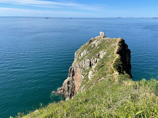 Narrow path along the edge of the cliff on the island of Shkota in August in sunny weather. Russia,...