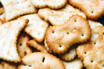 Saltine crackers on a plate. Crunchy party snack. Various shapes crackers background. Party food closeup texture. Baked crisps background.