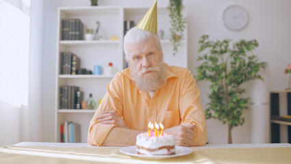 Portrait of a sad man in his 60s commemorating his birthday alone, coronavirus lockdown