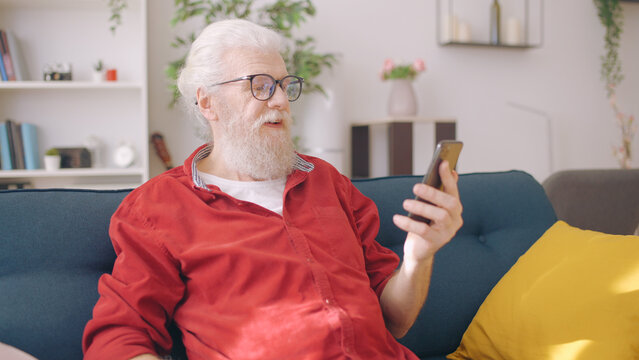 A Senior Man Uses His Smartphone To Make A Video Call, Perhaps For An Online Consultation Or To Chat With A Friend