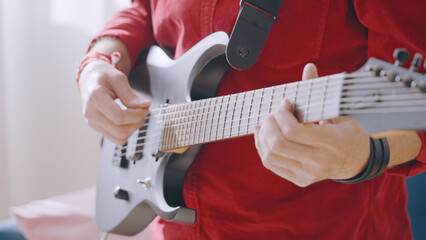Close-up of a man learning to play the electric guitar, finding entertainment in rock and roll