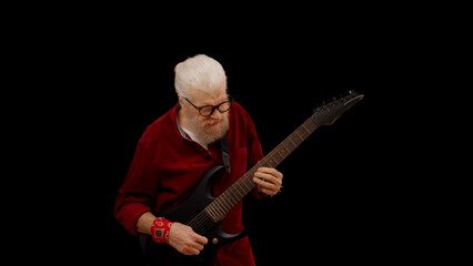 Contemporary senior man plays the electric guitar against a black background, showcasing his...