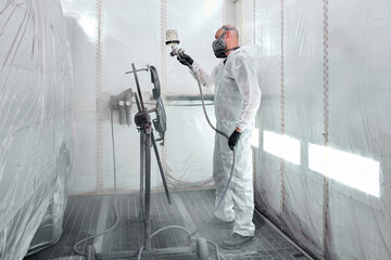 A skilled automotive technician meticulously coats the car parts in a state-of-the-art paint booth.