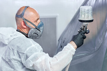 With the utmost attention to detail, a painter in a white jumpsuit revives the car's parts in an...