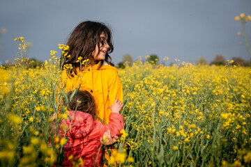 Naklejka na ściany i meble two children standing in a yellow blooming field