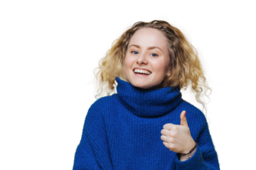 Exuberant young woman with blonde curly hair giving a thumbs up in a cozy blue turtleneck, against a yellow wall.