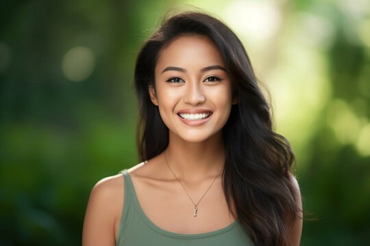 Portrait of a young beautiful smiling asian girl on a natural green background