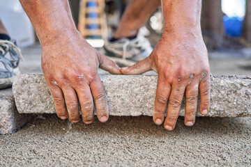 Installing new pavement or floor outside from large concrete tiles, closeup detail on male worker...